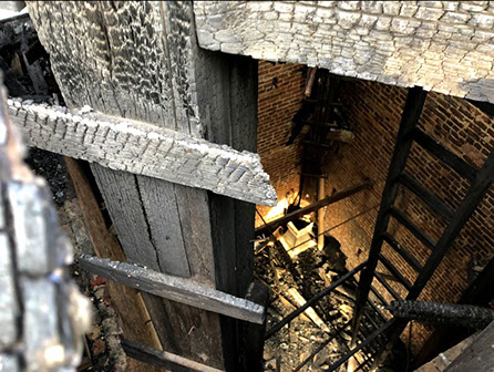 Downward view from scaffold of burnt materials to ground floor level, showing extent of fire damage.