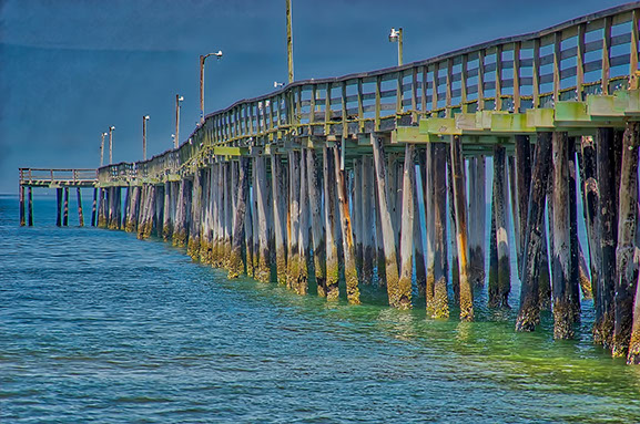 Closeip view of the pier which shows pilings worn and rotted over time from severe weather and harsh salt-sea environment.